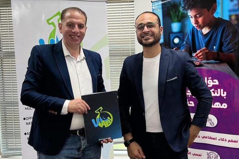 Two men standing side by side, one holding a VLAB folder